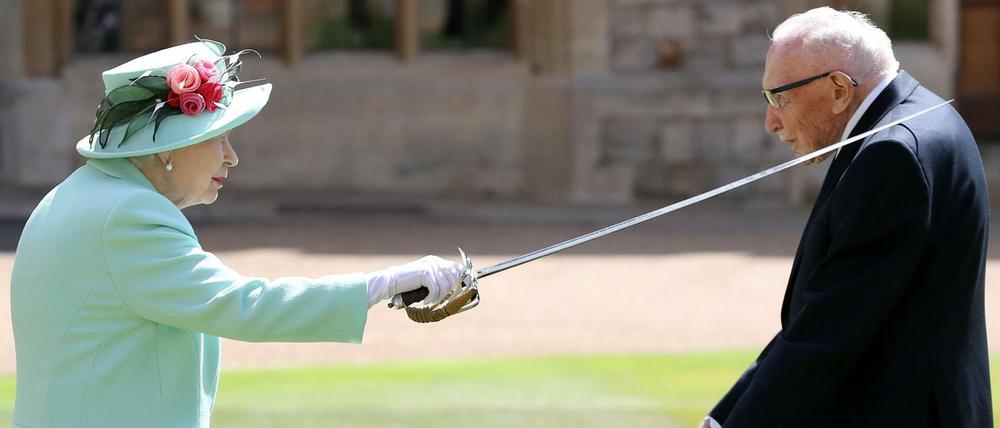 Königin Elizabeth II. (l) schlägt Sir Tom Moore (r), Weltkriegsveteran und Rekord-Spendensammler, auf Schloss Windsor zum Ritter.