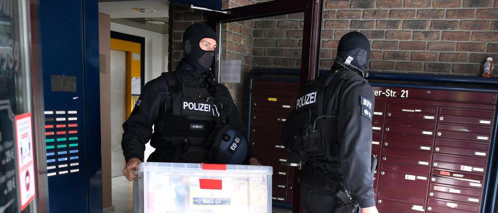 Polizisten tragen Kisten aus einem Gebäude, in dem die Polizei vorher eine Razzia gegen Clankriminalität durchgeführt hat.
