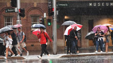 Passanten gehen am Freitag in Sydney durch den Regen.