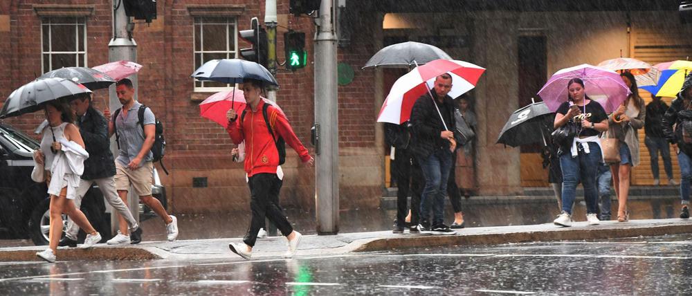 Passanten gehen am Freitag in Sydney durch den Regen.