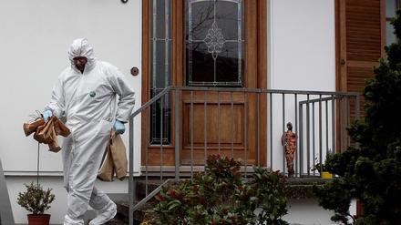 Ein Mitarbeiter der Spurensicherung trägt Papiertüten aus dem Wohnhaus des 49-jährigen Polizisten.