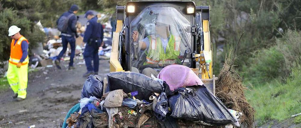 Ein Bulldozer räumt die Reste der Behausungen und Müll ab.