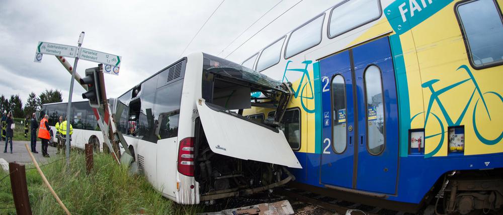 Ein Zug steht nach einem Zusammenstoß mit einem Schulbus auf den Gleisen. Bei dem Unfall wurde ein Mensch leicht verletzt.