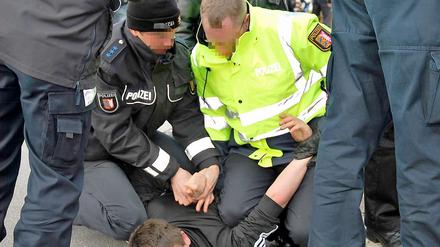 Polizisten nehmen einen gewalttätigen Demonstranten fest.