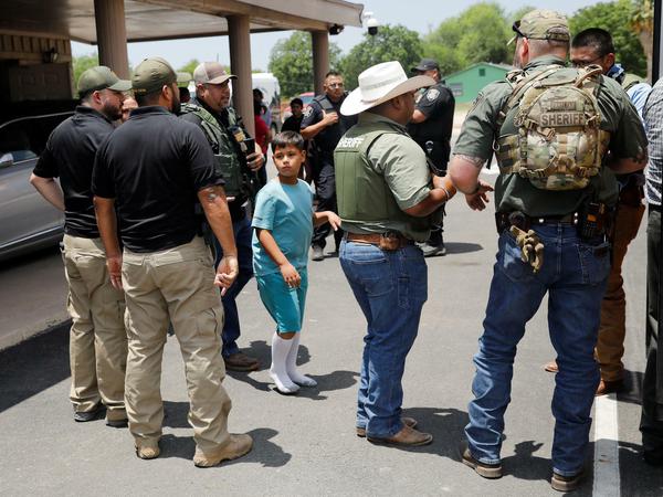 Ein Junge und Polizisten am Tatort des Schulmassakers in Texas