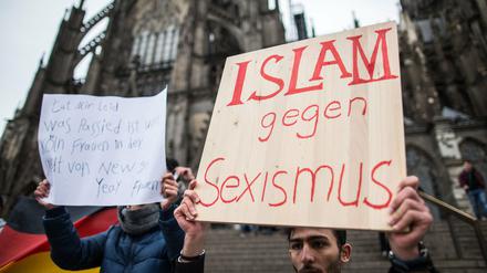 Ein Mann aus Syrien steht am Sonntag in Köln vor dem Hauptbahnhof und dem Dom mit einem Plakat "Islam gegen Sexismus". In Köln waren am Silvesterabend nach Polizeiangaben auf dem Platz vor dem Hauptbahnhof zahlreiche Frauen im Getümmel sexuell bedrängt und bestohlen worden.