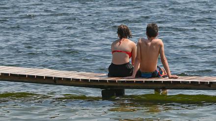 Zwei Badegäste sitzen auf einem Steg am Storkower See (Archivbild).