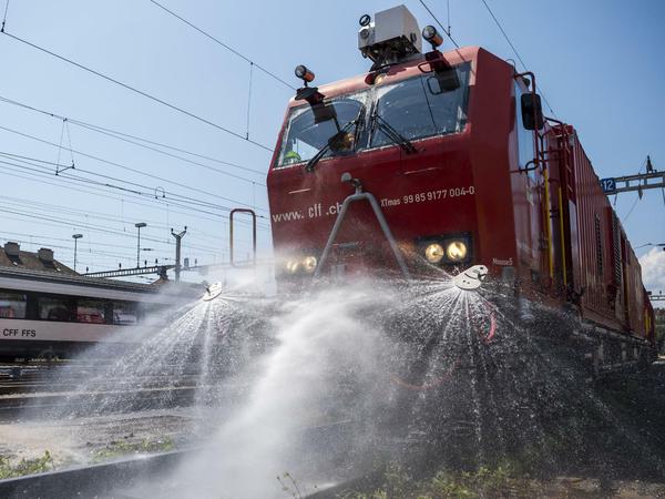 Maßnahmen gegen Hitze in der Schweiz: Eine SBB-Lokomotive mit Wassertank spritzt Wasser auf die Schienen, um sie an einem heißen Tag zu kühlen.