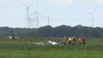 Feuerwehrleute neben einem abgestürzten Sportflugzeug auf eine Wiese nahe Sandstedt bei Cuxhaven (Niedersachsen). Drei Menschen kamen bei dem Unglück ums Leben. 