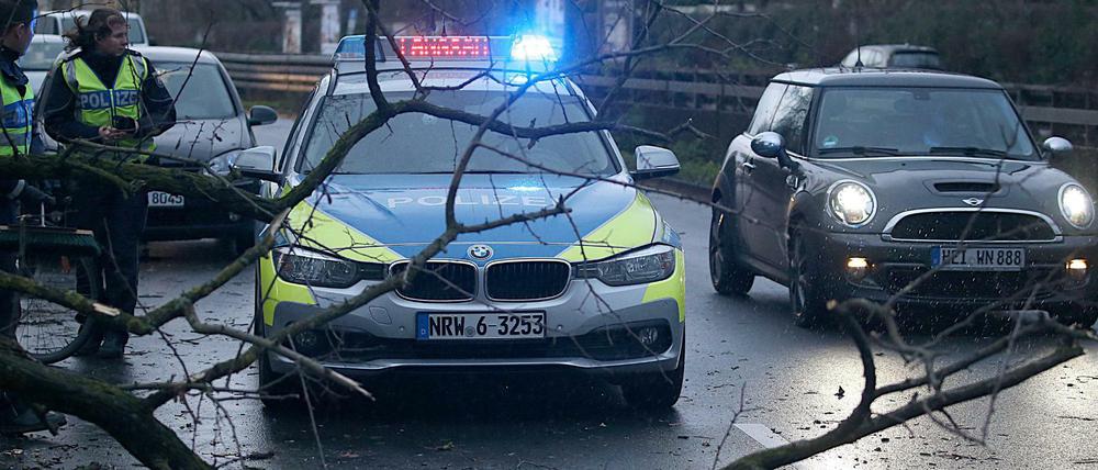 Polizisten beseitigen am Mittwochmorgen in Köln einen umgestürzten Baum von einer Straße. 