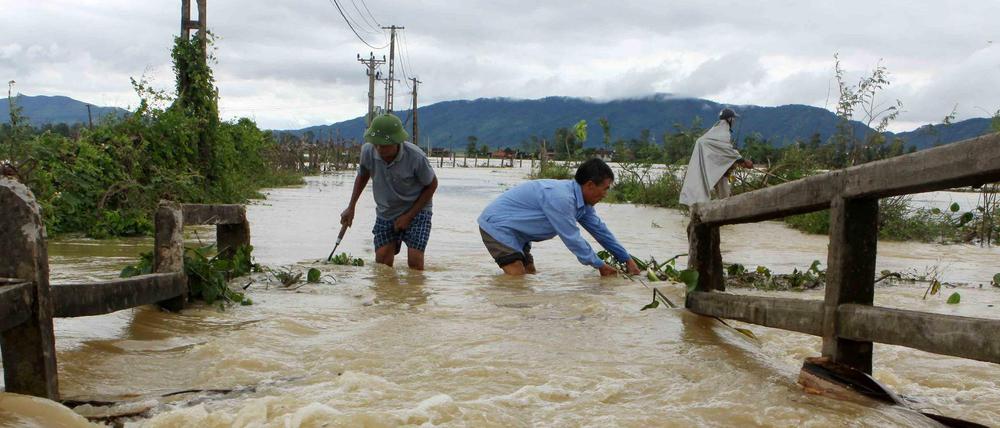 Männer waten durch ein überflutetes Gebiet in der zentralen Provinz Nghe An.