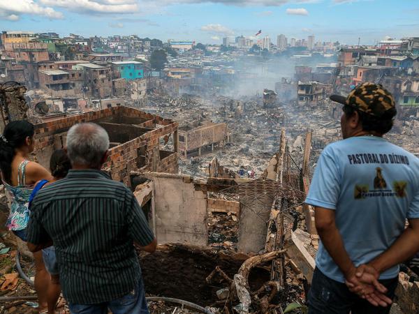 Bewohner des Armenviertels betrachten die zerstörten Häuser.