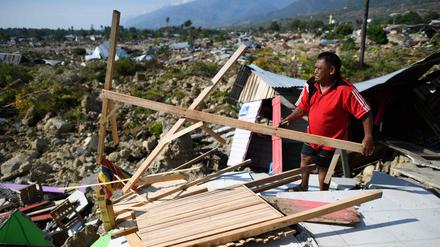 Ein Überlebender des Tsunamis sucht in Trümmern nach brauchbaren Resten. 