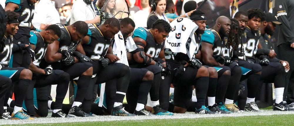 Protest am Spielfeldrand. Die Footballer des NFL-Teams Jacksonville Jaguars knien gemeinsam während der Nationalhymne nieder.