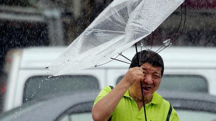 Ein Mann in Taiwan hält einen Regenschirm während der Taifun wütet. 