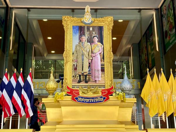Vor einem Gebäude steht ein großes Foto von Maha Vajiralongkorn und seiner Frau Suthida.