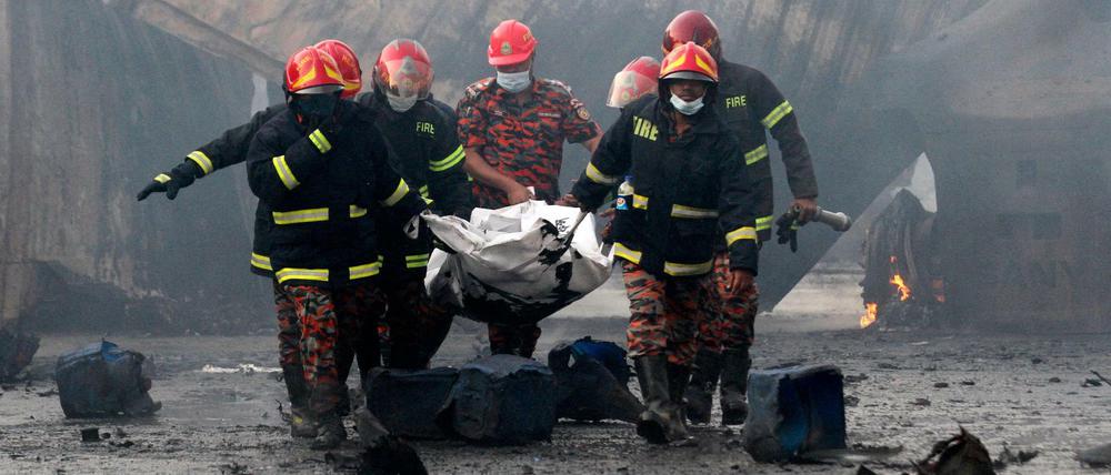 Feuerwehrleute bergen ein Opfer des Brandes in einem Containerlage in Bangladesch. 