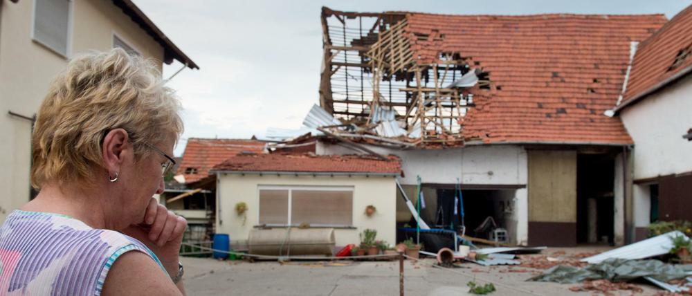 Völlig zerstört ist eine Scheune in Framersheim (Rheinland-Pfalz) nach einem Tornado am Dienstag vor der die Besitzerin steht. Innerhalb von Sekunden hatte die Windhose am Abend mehrere Häuser zerstört und Autos beschädigt. Der Ort wurde abgeriegelt.