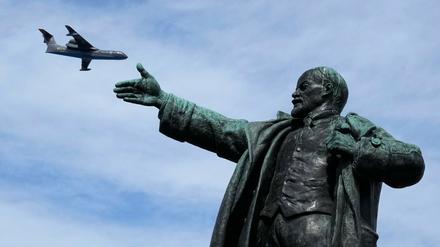 Ein Militärflugzeug fliegt über einer Lenin-Statue am Himmel. In Estland werden sowjetische Denkmäler künftig nicht zu sehen sein. 