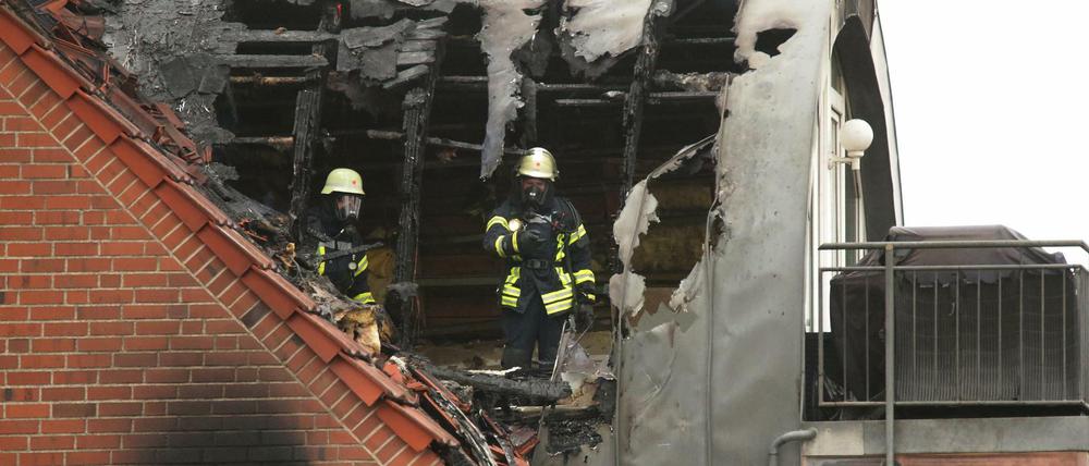 Feuerwehrleute suchen in dem beschädigten Wohnhaus nach Spuren.