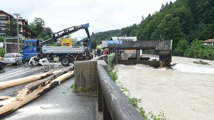 Ein Baumstamm wird bei Unwetter und Hochwasser in Bayern im Berchtesgadener Land aus dem Wasser geholt.
