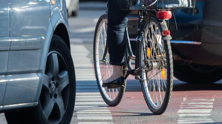 Eine Fahrradfahrerin radelt auf einem Radweg, während Autos rechts abbiegen. 