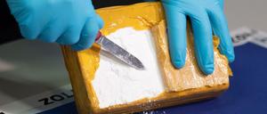 Ein Polizist öffnet ein Paket mit Kokain, das sichergestellt wurde (Symbolbild).