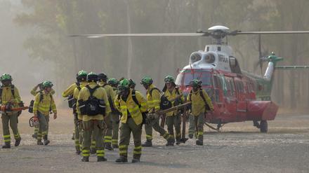 Feuerwehrleute, die die ganze Nacht über am Waldbrand gearbeitet haben, kommen mit dem Hubschrauber am Kommandoposten in Pujerra an.