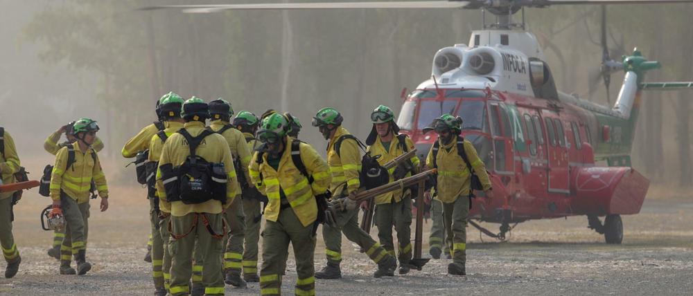 Feuerwehrleute, die die ganze Nacht über am Waldbrand gearbeitet haben, kommen mit dem Hubschrauber am Kommandoposten in Pujerra an.