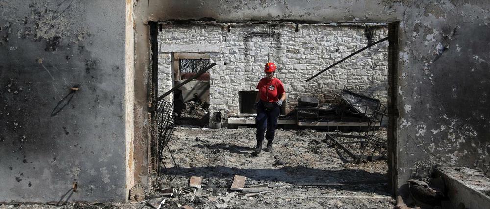 Griechenland, Mati: Ein Mitglied eines Rettungsteams sucht in einem ausgebrannten Haus nach Vermissten.