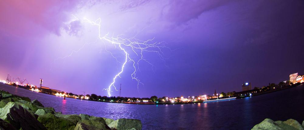 Blitze zucken am Sonntag über dem Hafen von Rostock während eines Gewitters über den Himmel.