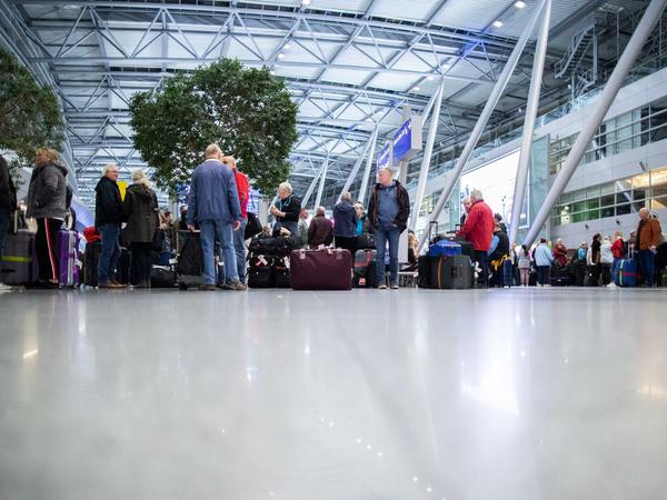 Reisende warten mit ihrem Gepäck am Flughafen Düsseldorf
