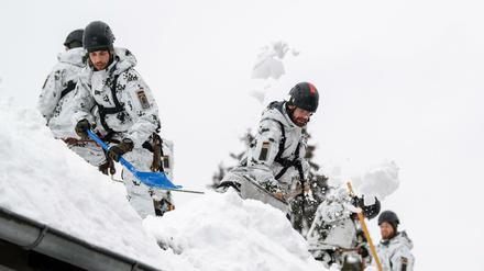 Einsatzkräfte der Bundeswehr befreien ein Dach im Umkreis von Bad Tölz von Schneemassen.