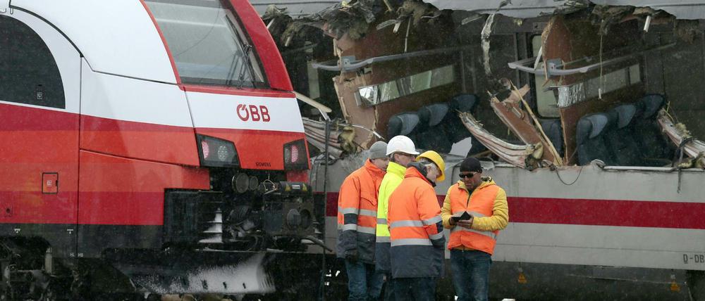 Mitarbeiter der Österreichischen Bundesbahnen (ÖBB) stehen vor den zwei durch eine Kollision beschädigten Zügen. 