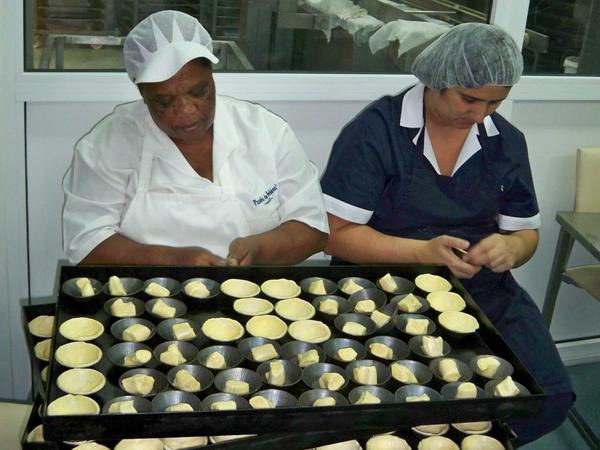 Echte Handarbeit: Die Frauen drücken den Bätterteig für die Pastetchen in Formen.