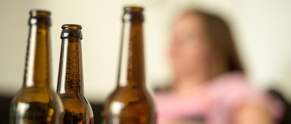  Eine junge Frau sitzt hinter leeren Bierflaschen.