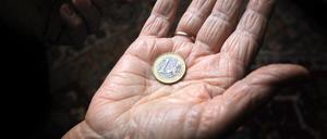 Eine 83-jährige Frau hält eine Euromünze in der geöffneten Handfläche.