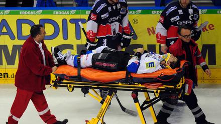 Sanitäter schieben den nach einem Zweikampf auf dem Spielfeld liegengebliebenen Ingolstädter Verteidiger Bruno St. Jacques auf einer Trage vom Eis.