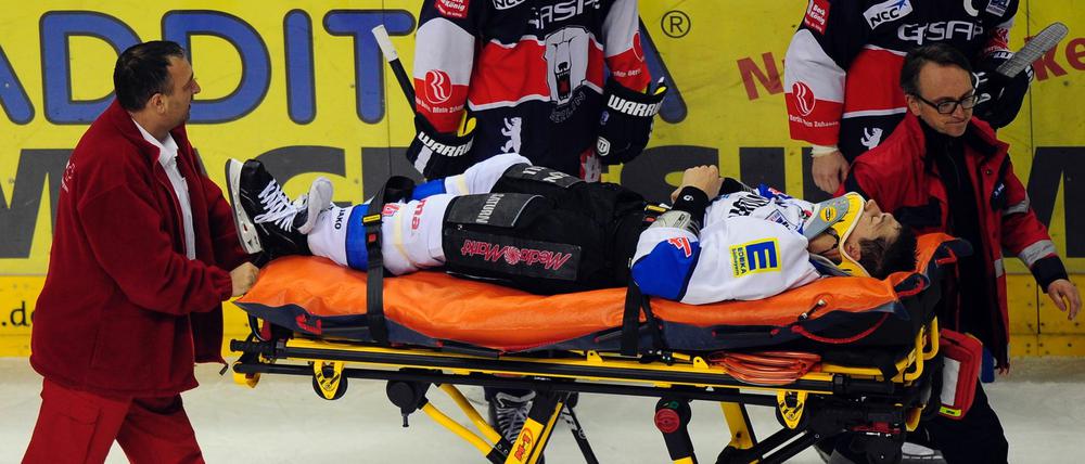 Sanitäter schieben den nach einem Zweikampf auf dem Spielfeld liegengebliebenen Ingolstädter Verteidiger Bruno St. Jacques auf einer Trage vom Eis.