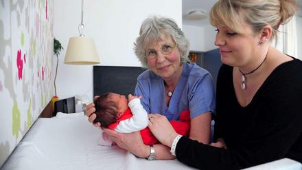 Bei der Arbeit. Hebamme Barbara Peter (M.) mit Mutter und Neugeborenem.