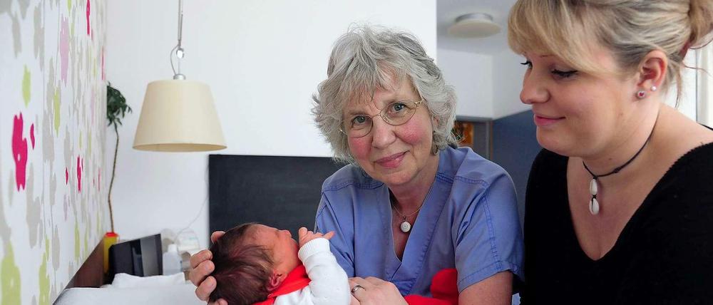 Bei der Arbeit. Hebamme Barbara Peter (M.) mit Mutter und Neugeborenem.