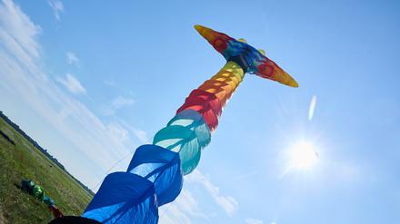 Auf dem Tempelhofer Feld startet ein langer bunter Drachen beim 10. Festival der Riesendrachen am spätsommerlich blauen Himmel der Sonne entgegen.