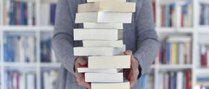 Eine Frau hält einen Bücherstapel.