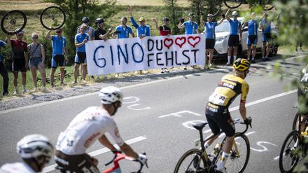 Das Fahrerfeld fährt an Fans vorbei, die dem nach einem Sturz verstorbenen Schweizer Gino Mäder gedenken.