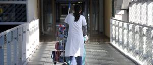 Eine Putzkraft schiebt einen Wagen durch ein Krankenhaus.