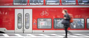 Eine Frau geht am Frankfurter Hauptbahnhof an einer Regionalbahn vorbei.