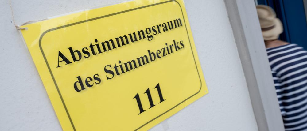 Ein Schild mit dem Schriftzug «Abstimmungsraum des Stimmbezirks 111» hängt am Eingang eines Abstimmungsraums.