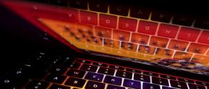 Die Tastatur eines Laptops spiegelt sich in dessen Bildschirm. 
