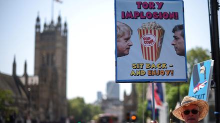 Ein Demonstrant hält ein Plakat, das die Beziehung und die politische Situation zwischen dem britischen Premierminister Rishi Sunak und seinem Vorgänger Boris Johnson karikiert.