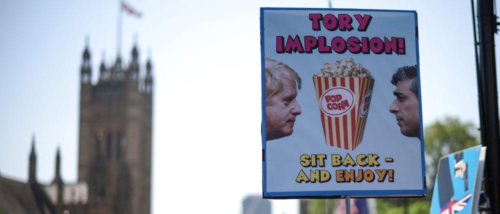 Ein Demonstrant hält ein Plakat, das die Beziehung und die politische Situation zwischen dem britischen Premierminister Rishi Sunak und seinem Vorgänger Boris Johnson karikiert.